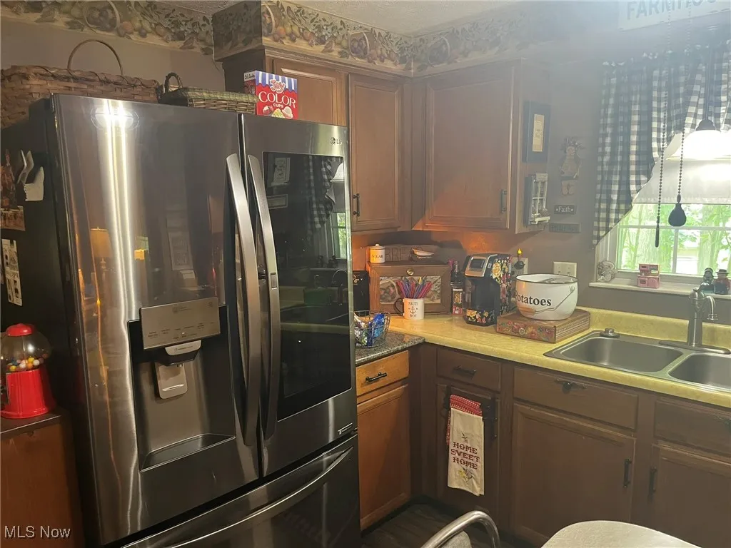 Kitchen featuring smart refrigerator, light countertops, and brown cabinetry