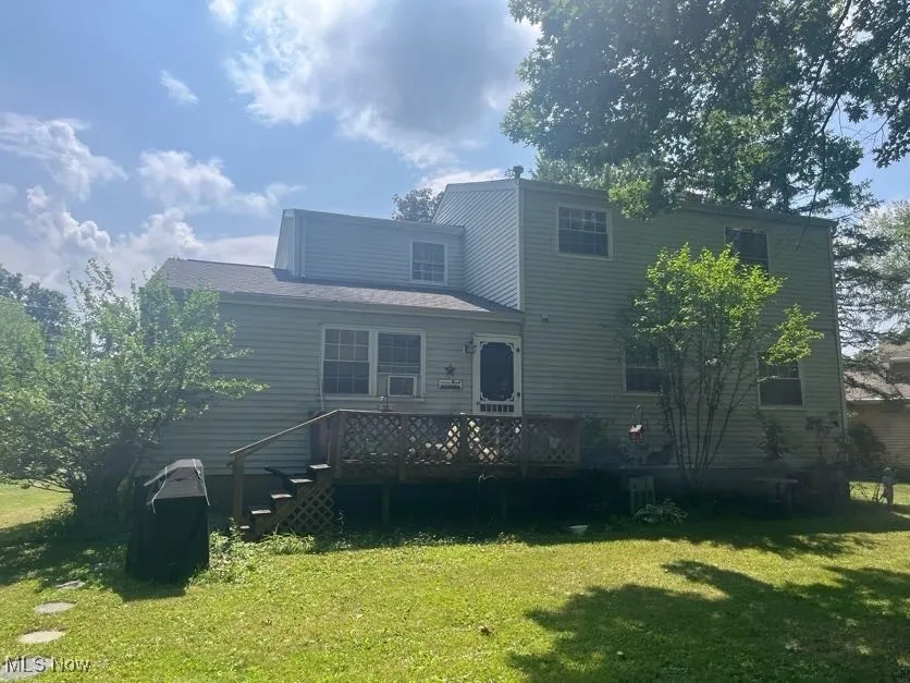 Back of property with a lawn, a deck, and stairs