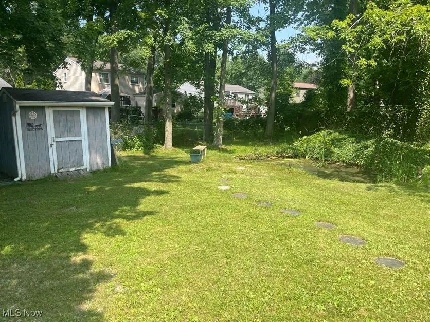 View of green lawn featuring a storage shed