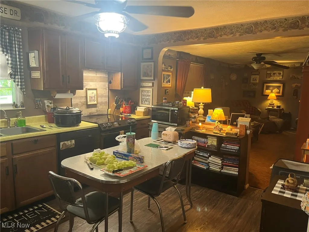 Kitchen featuring a ceiling fan, electric range, stainless steel microwave, dark wood-style flooring, and arched walkways