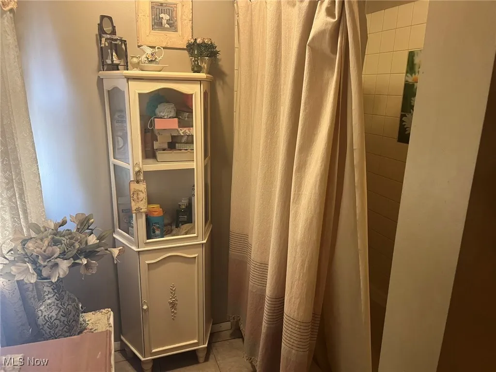 Full bath with tile patterned floors and a shower with curtain