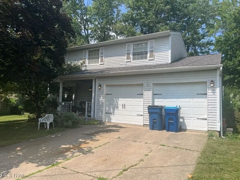 View of front facade featuring covered porch, driveway, and a garage