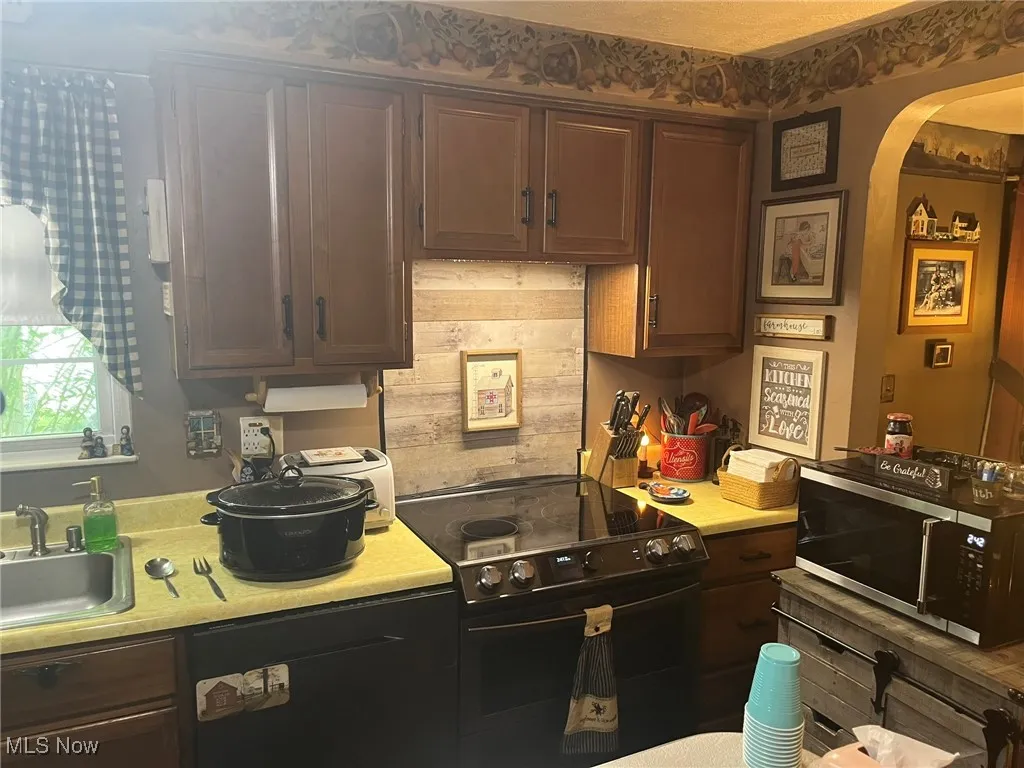 Kitchen featuring stainless steel microwave, electric range, dishwasher, and light countertops