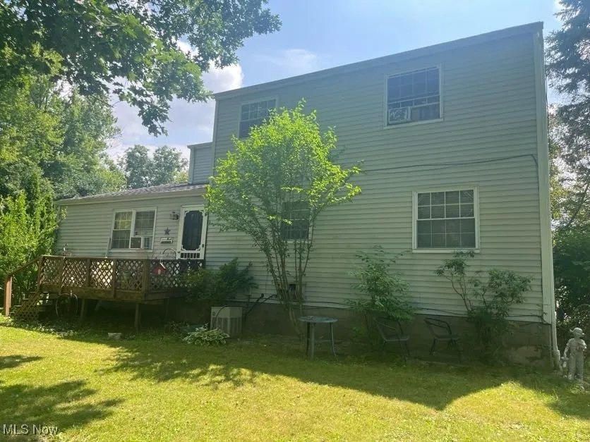 Back of house featuring a lawn and a deck