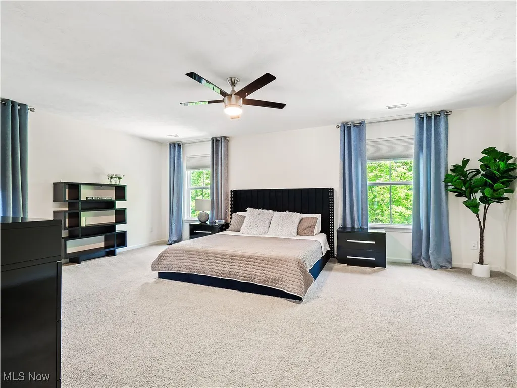 Carpeted bedroom featuring ceiling fan and baseboards