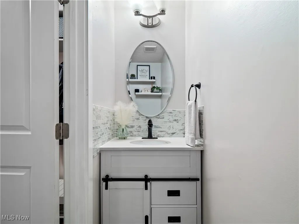 Bathroom featuring vanity and tasteful backsplash