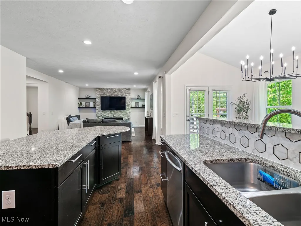 Kitchen featuring dark cabinetry, dark wood-style flooring, a fireplace, recessed lighting, and light stone countertops