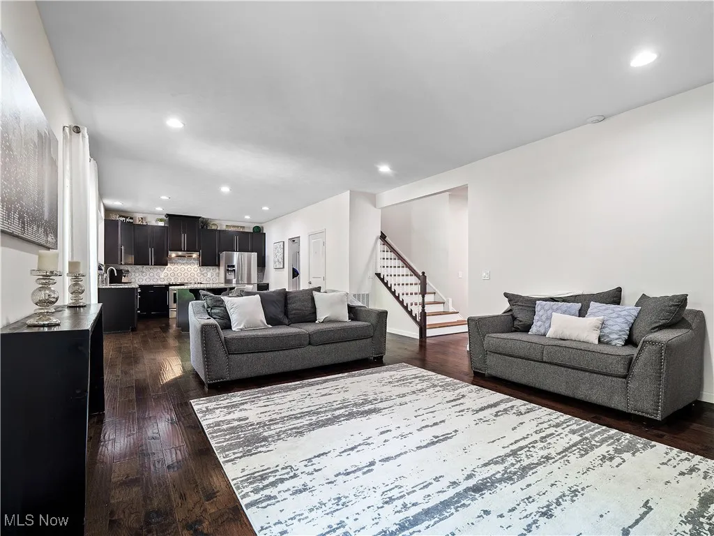 Living area featuring stairs, recessed lighting, and dark wood-style flooring