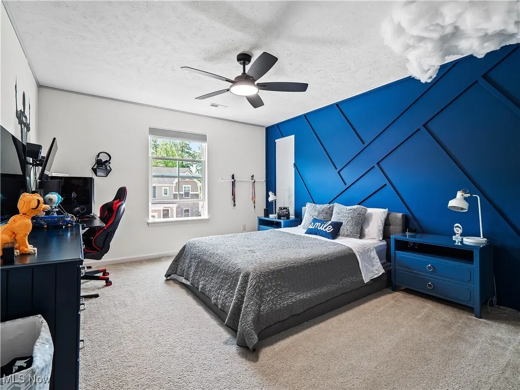 Carpeted bedroom with ceiling fan and a textured ceiling