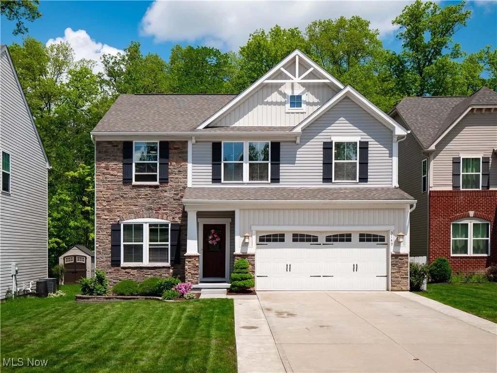 Craftsman inspired home featuring board and batten siding, stone siding, concrete driveway, an attached garage, and a front yard