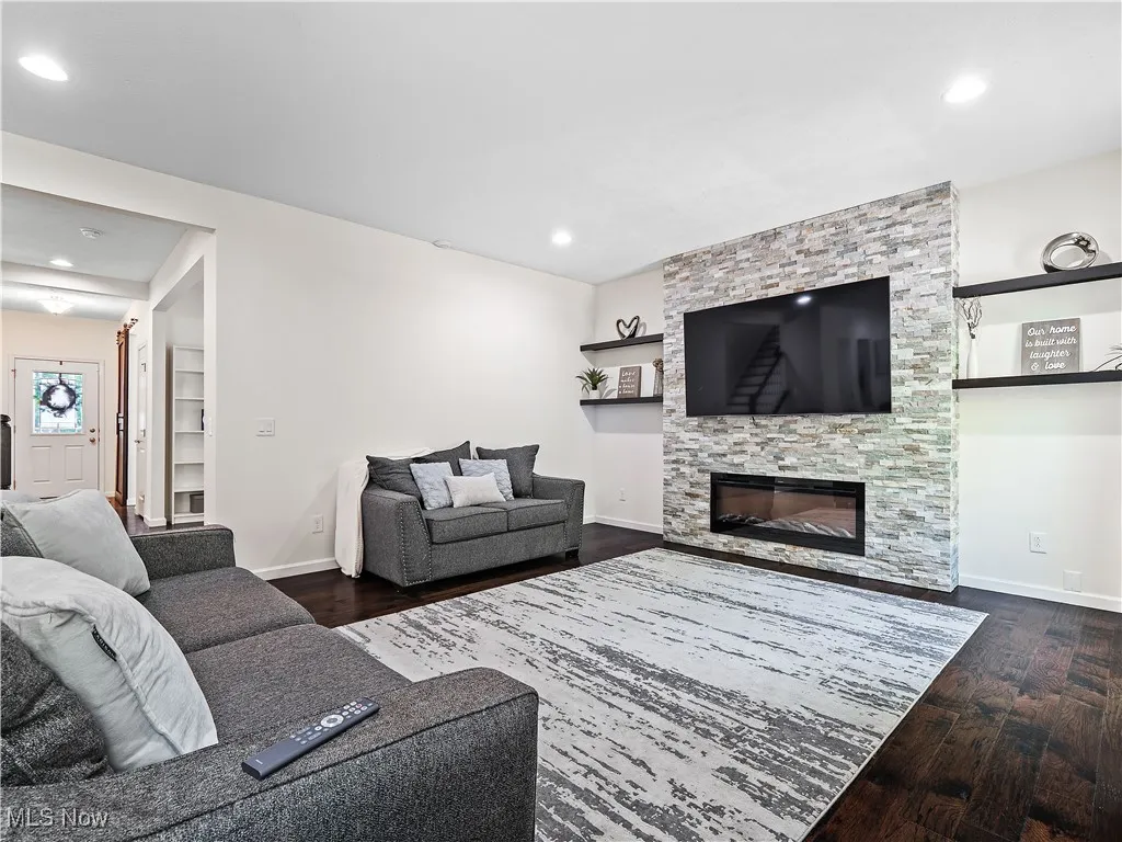 Living room featuring dark wood-style flooring, a stone fireplace, and recessed​​‌​​​​‌​​‌‌​‌‌​​​‌‌​‌​‌​‌​​​‌​​ lighting