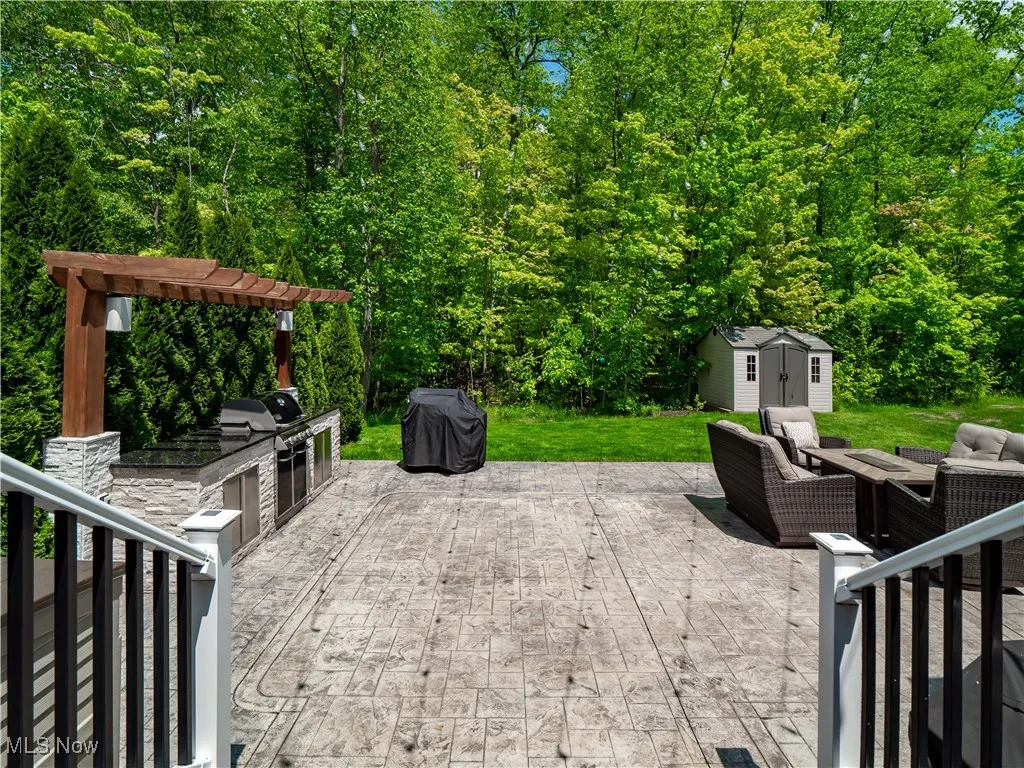 View of patio with an outdoor living space, exterior kitchen, and a shed