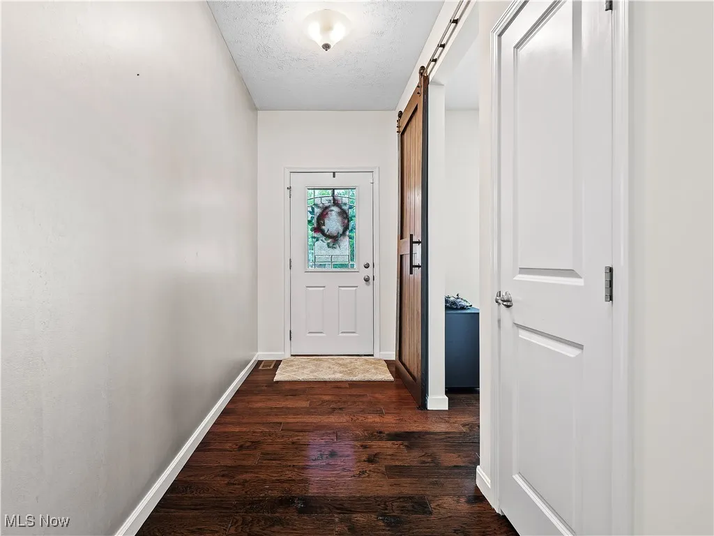 Doorway featuring dark wood-style floors, a barn door, and a textured ceiling