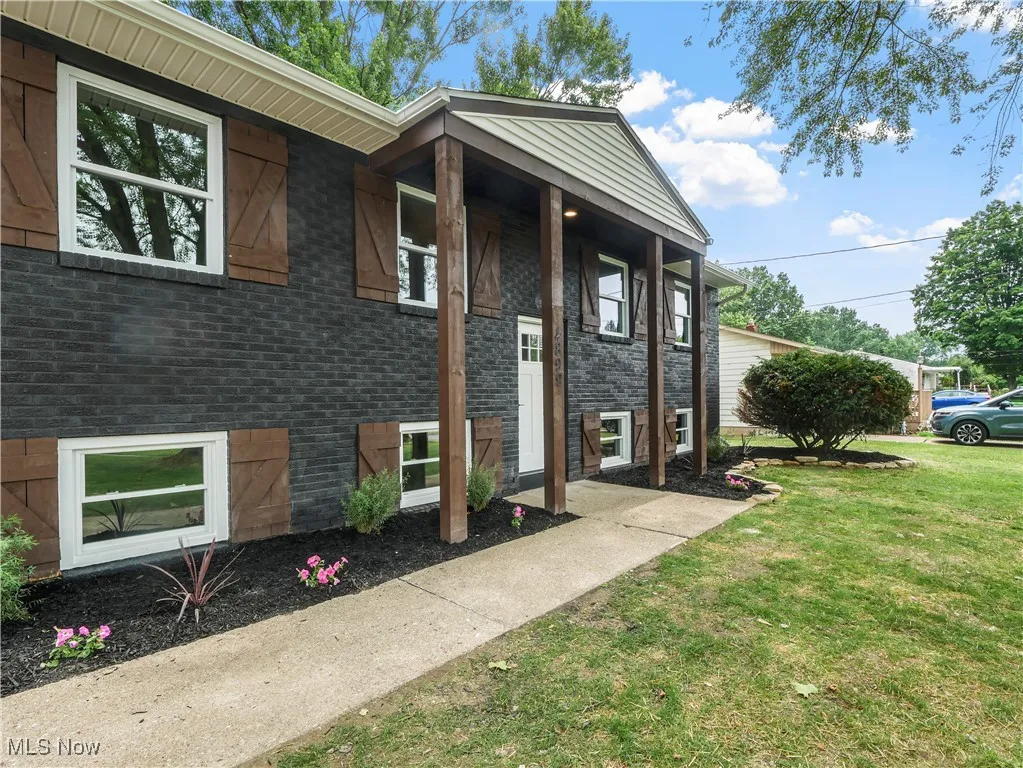 Entrance to property with a lawn and brick siding