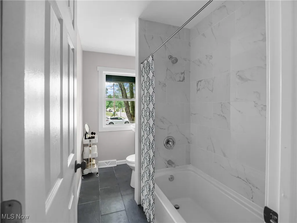 Full bathroom featuring shower / bath combination with curtain and tile patterned floors