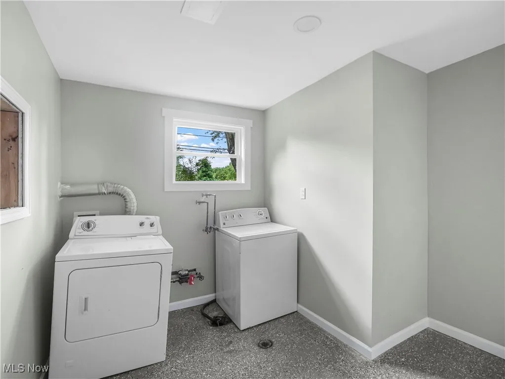 Laundry room with washer and clothes dryer and baseboards