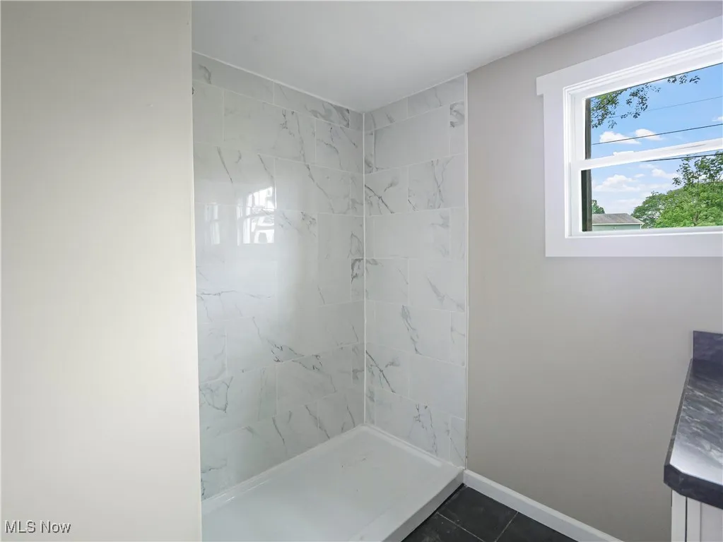 Bathroom featuring tile patterned floors and a tile shower