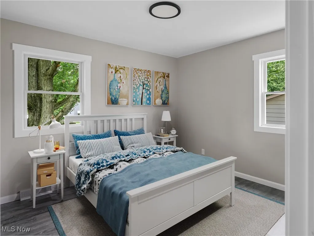 Bedroom with multiple windows and dark wood-style flooring