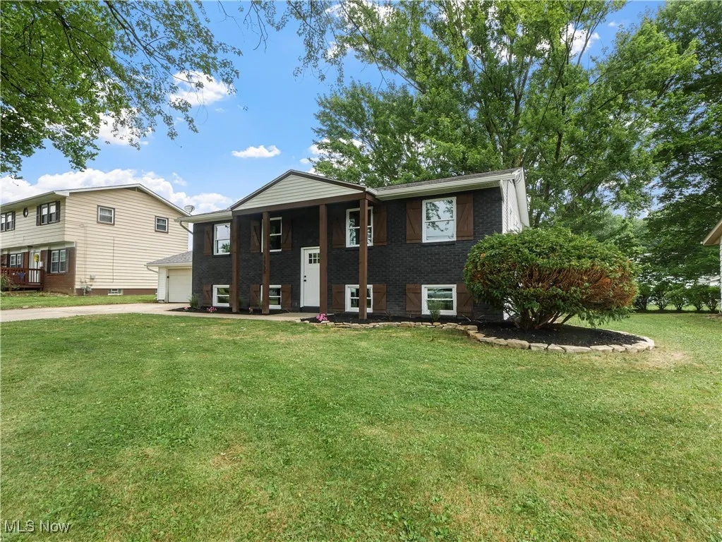 Bi-level home featuring concrete driveway, a front yard, and brick siding