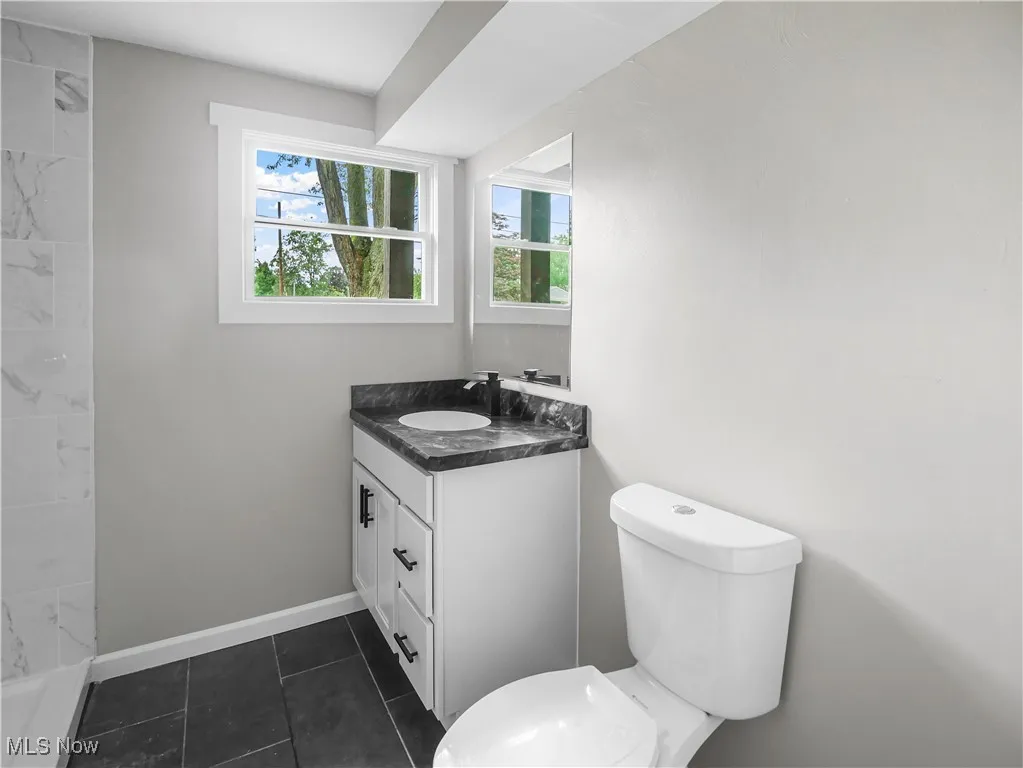 Bathroom with vanity, a shower, and tile patterned floors