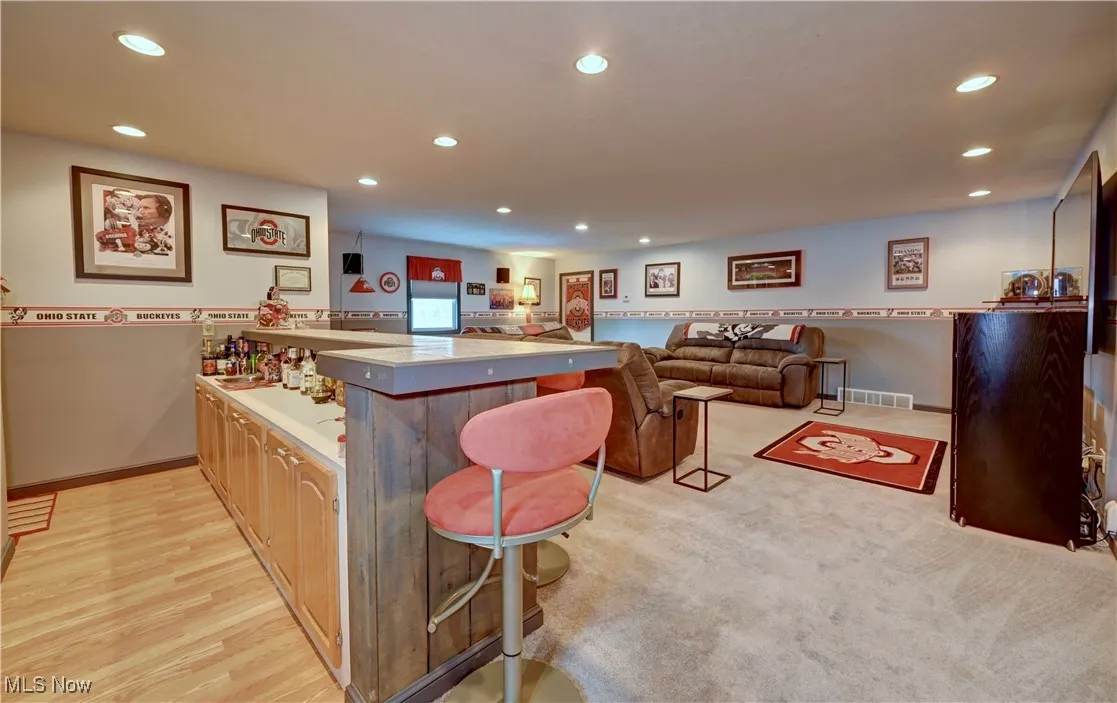 Kitchen with a peninsula, recessed lighting, a kitchen bar, light wood-style floors, and light countertops