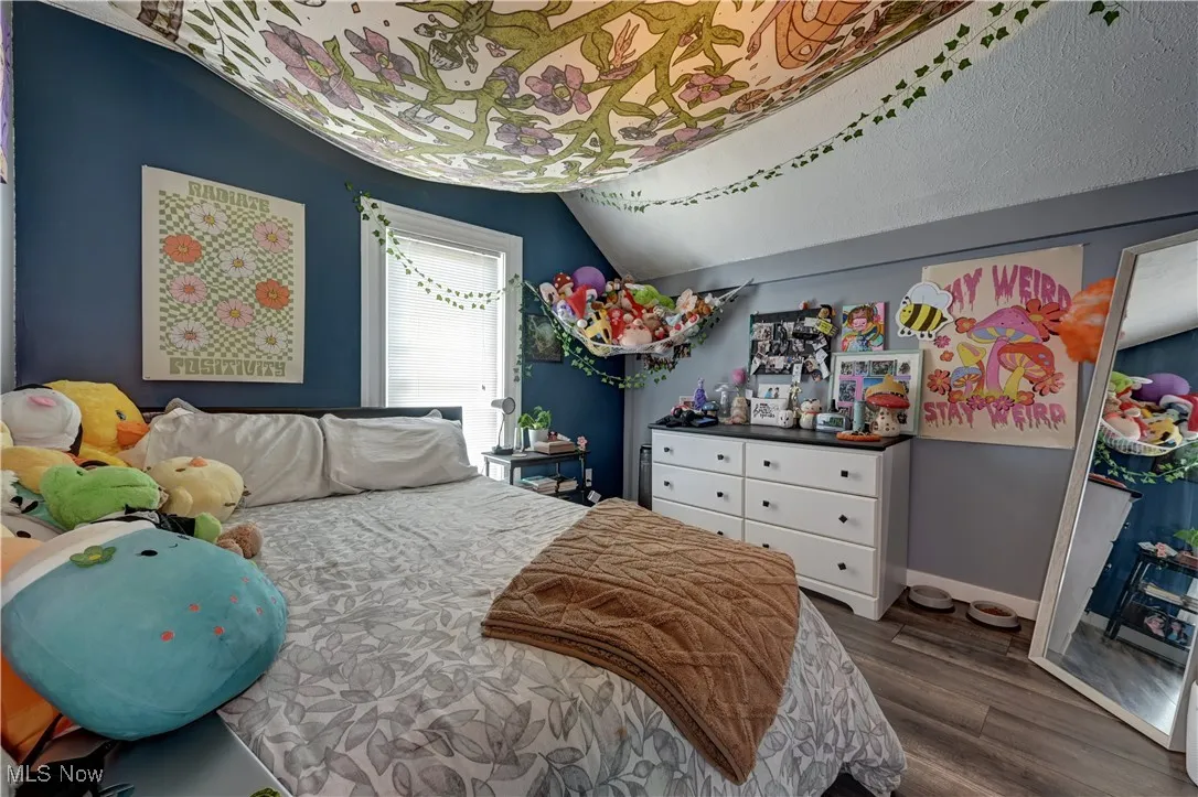 Bedroom with dark wood-style floors and vaulted ceiling