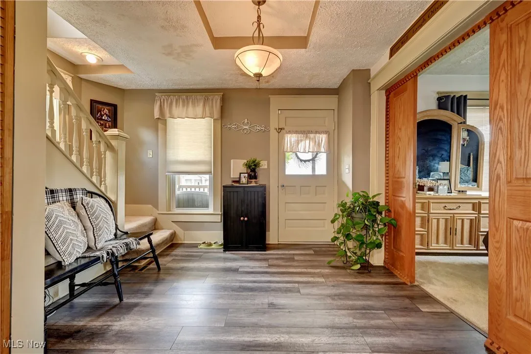 Entrance foyer with a textured ceiling, stairs, and wood finished floors