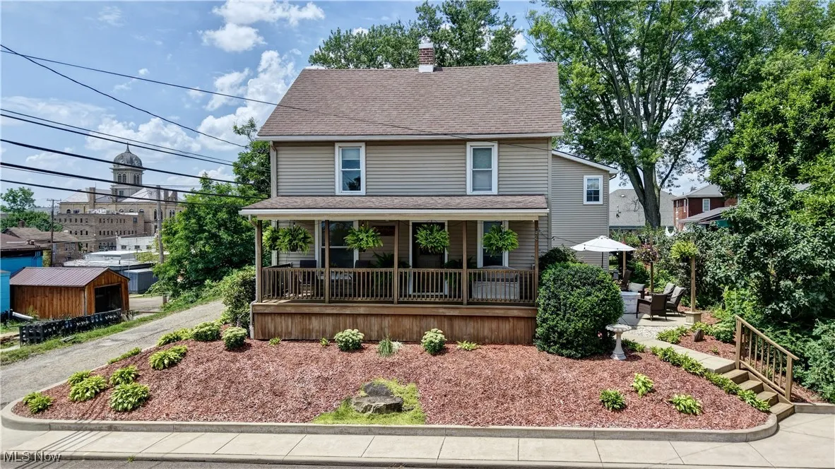 American foursquare style home with a porch, a chimney, and roof with shingles