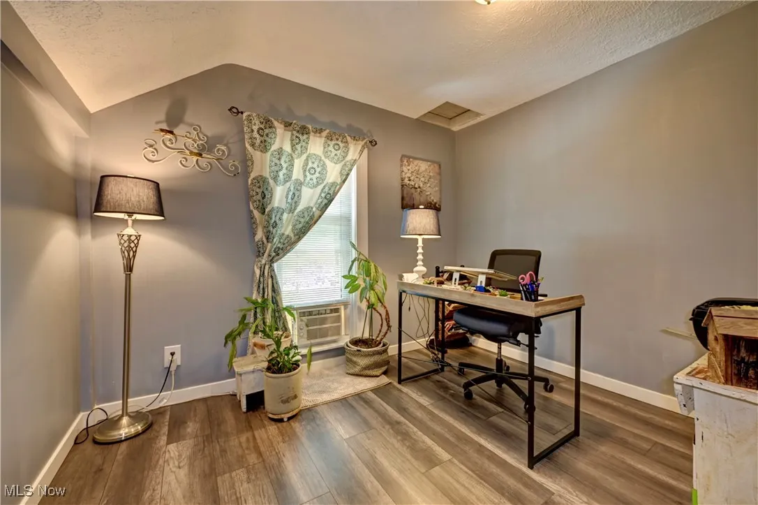 Office space with wood finished floors, a textured ceiling, and vaulted ceiling