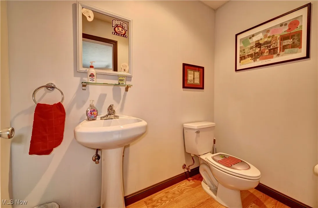 Half bath with toilet and wood finished floors