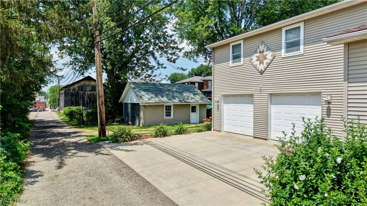 View of front of home with driveway, a garage, and an outdoor structure