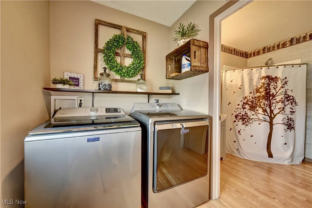 Laundry room with separate washer and dryer and light wood-style flooring