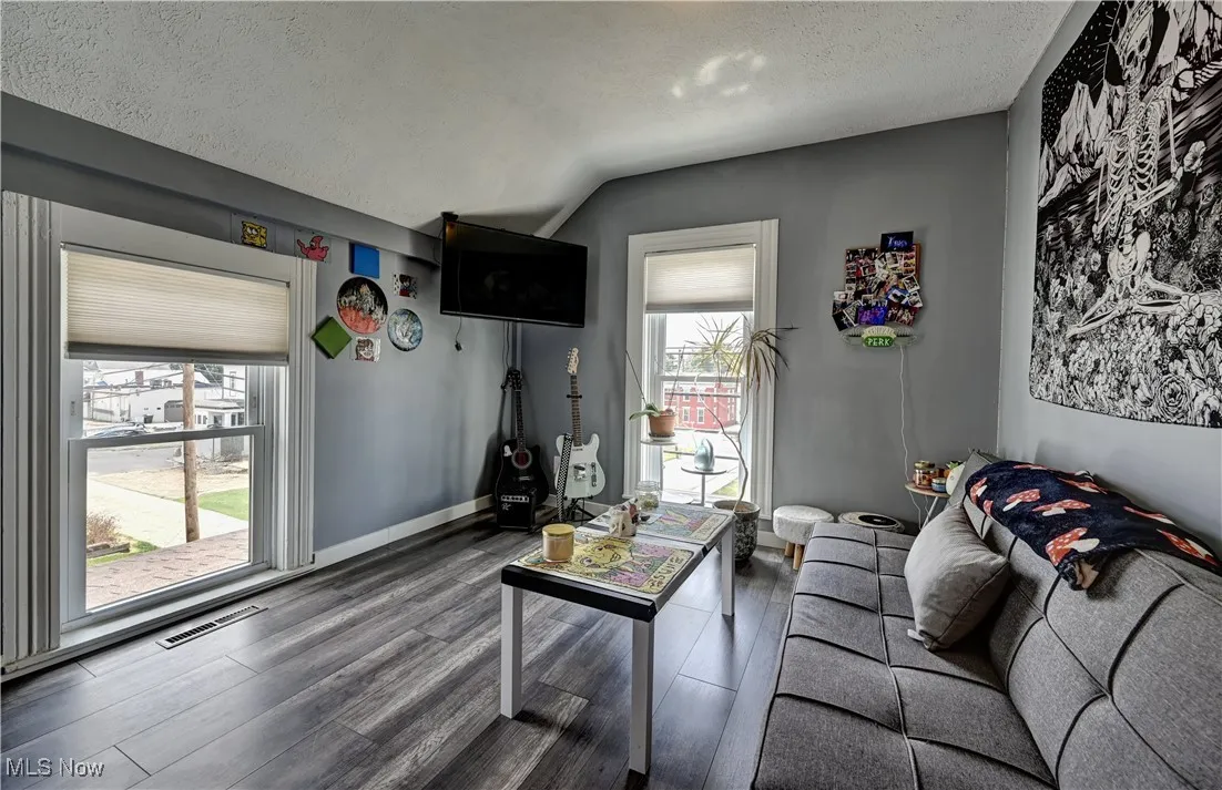 Living area featuring wood finished floors, a textured ceiling, healthy amount of natural light, and lofted ceiling