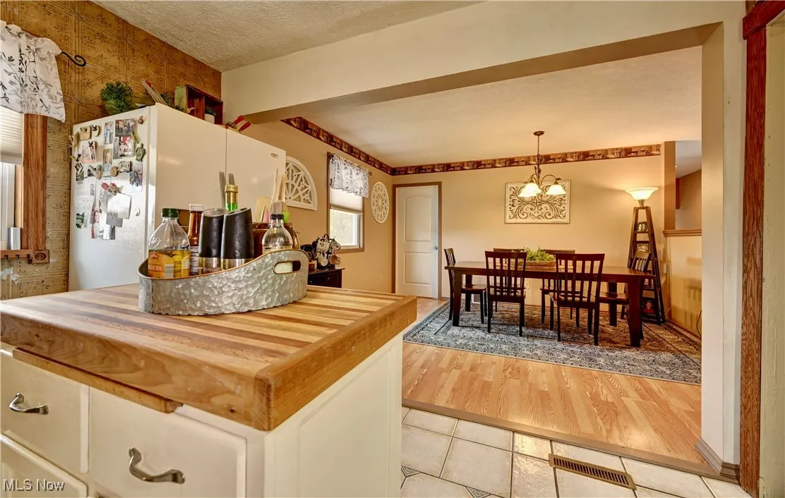 Kitchen with freestanding refrigerator, light tile patterned floors, a chandelier, and pendant lighting