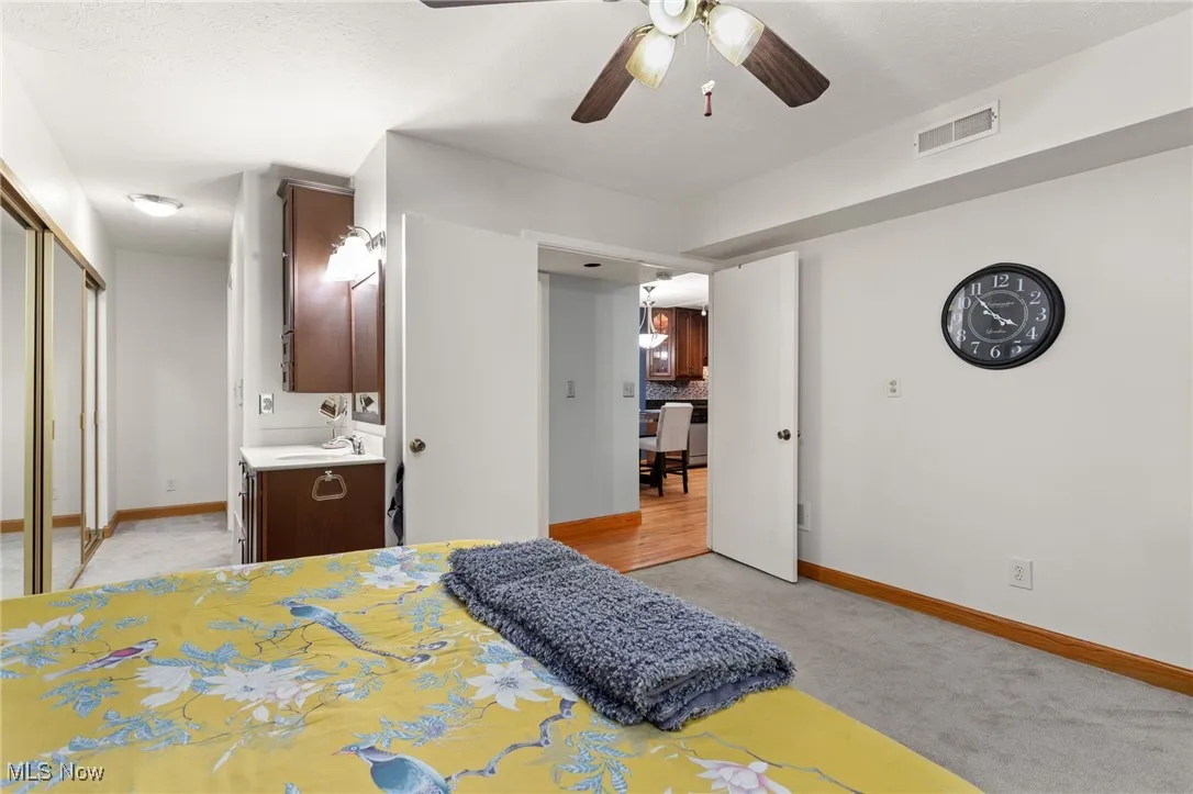 Bedroom featuring light carpet, ensuite bath, a closet, and ceiling fan