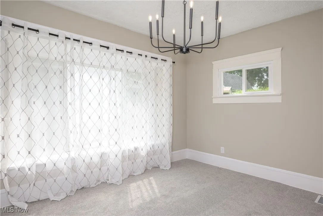 Spare room with a chandelier, carpet, and a textured ceiling