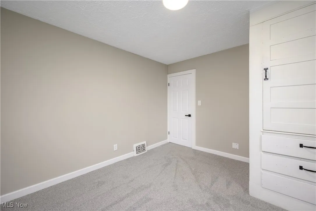 Empty room with carpet and a textured ceiling