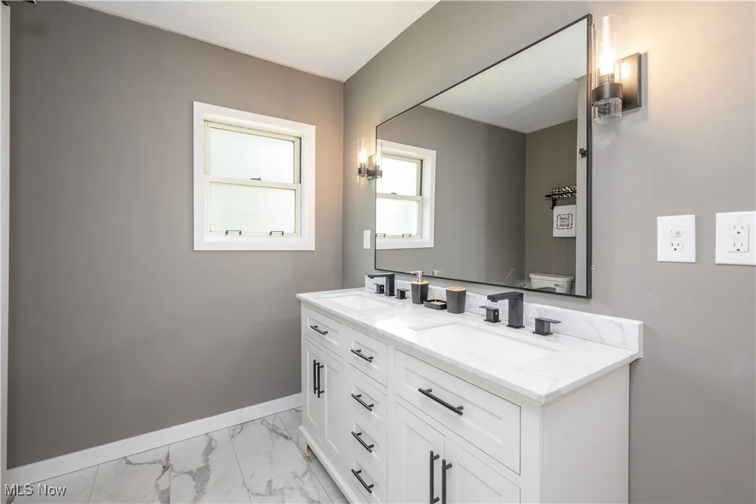 Bathroom with marble look tile flooring and double vanity