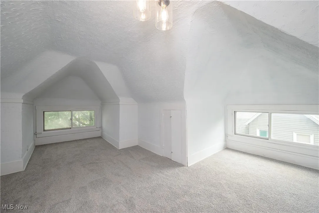 Bonus room with carpet, vaulted ceiling, and a textured ceiling