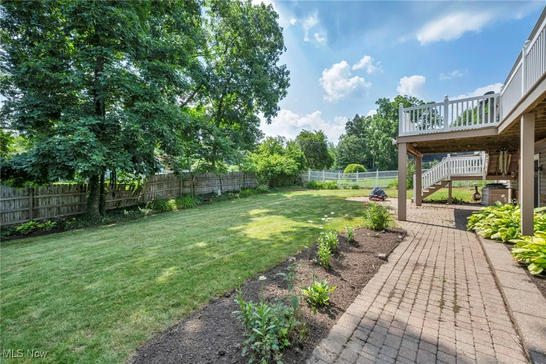 Fenced backyard with stairs, a deck, and a patio.