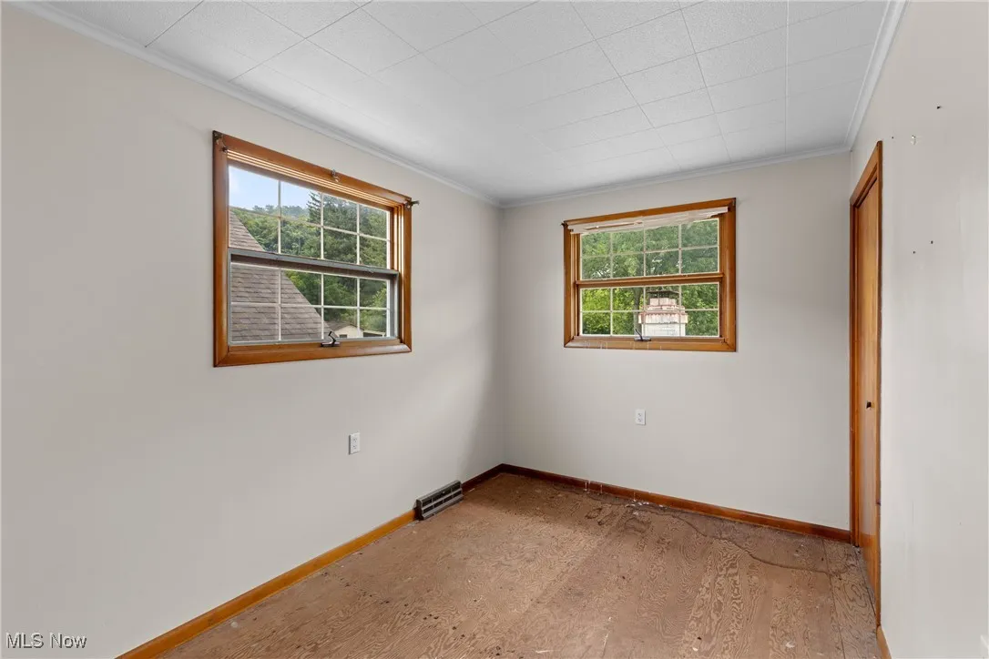 Empty room featuring ornamental molding and wood finished floors