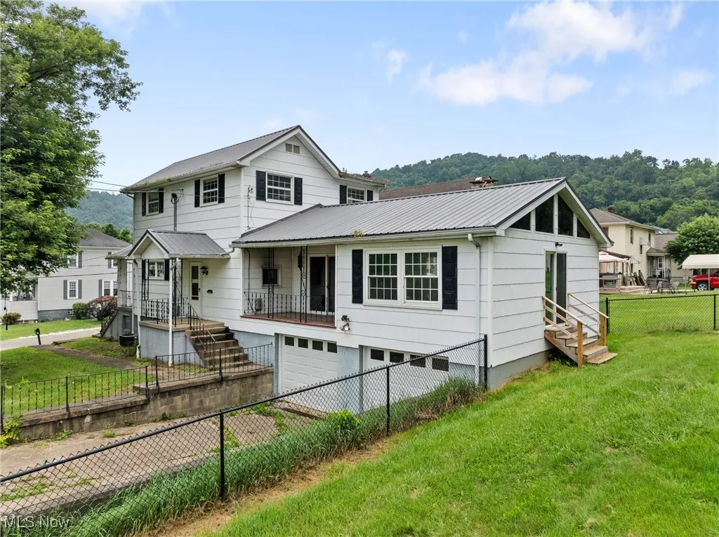 View of front of house featuring an attached garage, a metal roof, and a fenced backyard