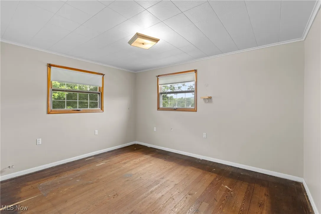 Unfurnished room featuring plenty of natural light, ornamental molding, and wood-type flooring