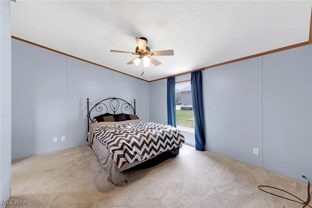 Bedroom with carpet floors, crown molding, and a ceiling fan