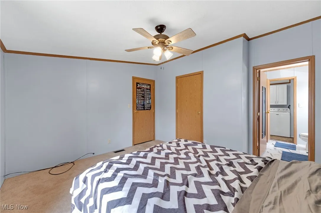 Unfurnished bedroom ornamental molding, carpet flooring, and ceiling fan