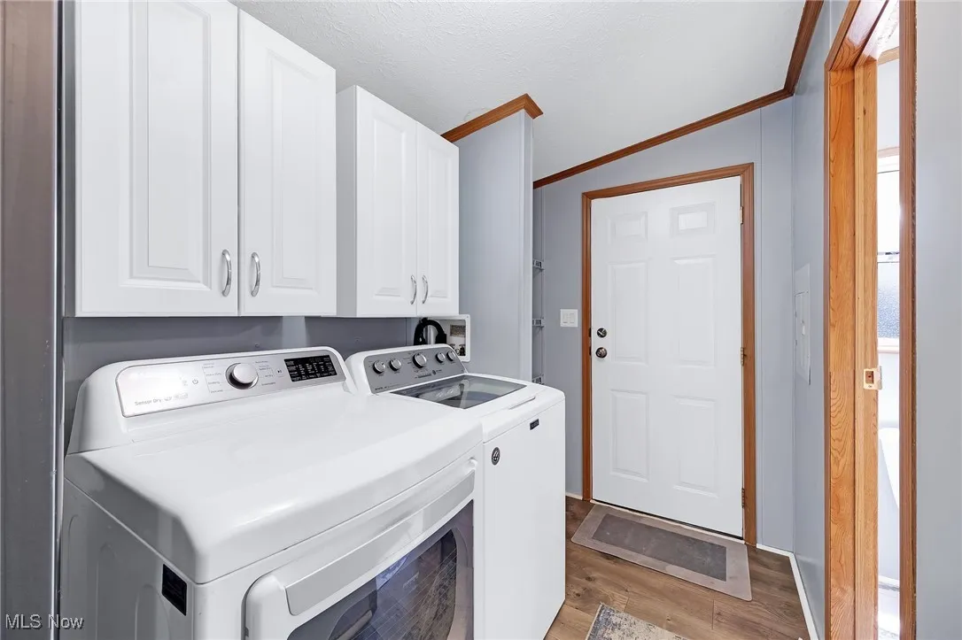 Washroom featuring separate washer and dryer, cabinet space, ornamental molding, and light wood-style flooring