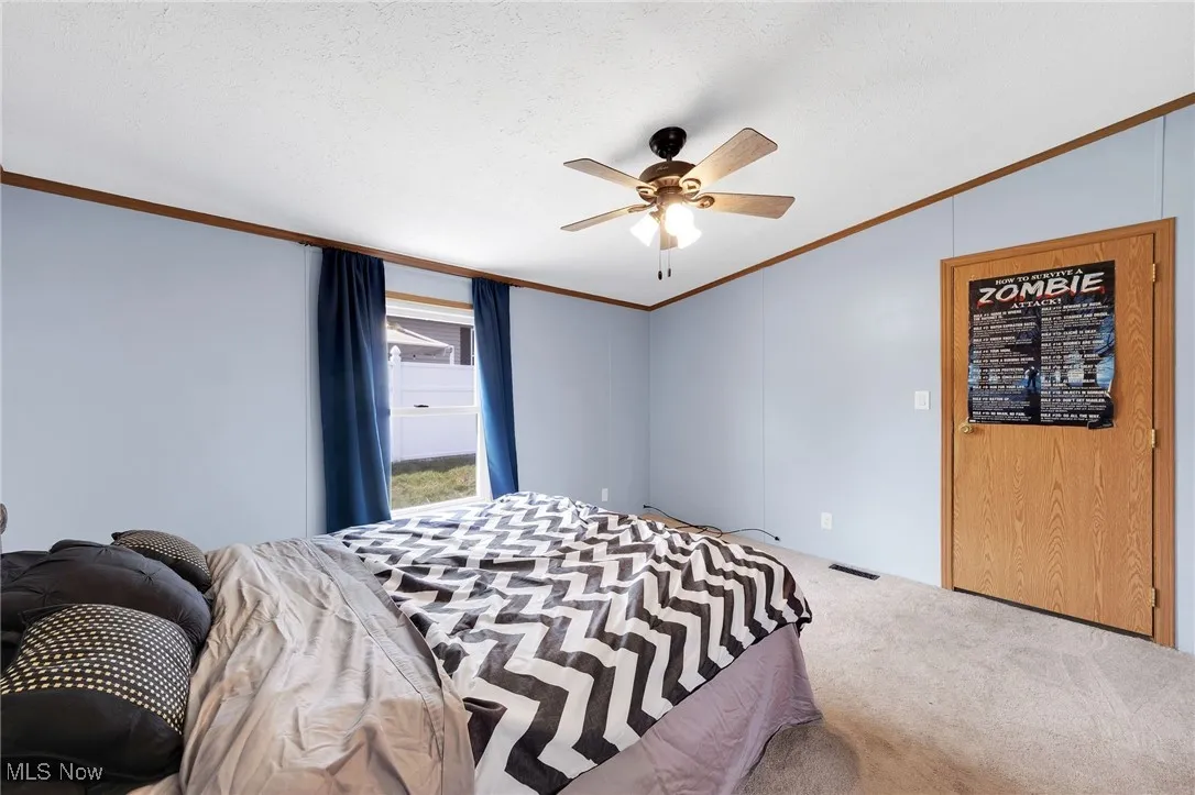 Carpeted bedroom with vaulted ceiling, ornamental molding, and a ceiling fan