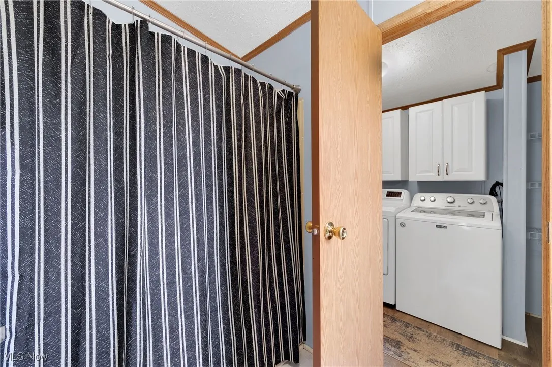 Laundry room with light wood-type flooring, cabinet space, and washing machine and dryer