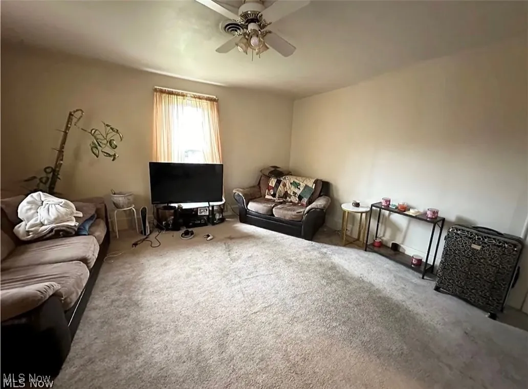 Carpeted living area featuring a ceiling fan