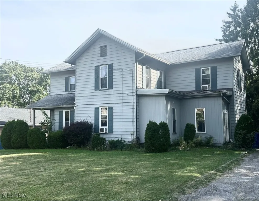 View of front facade featuring a front lawn and a shingled roof